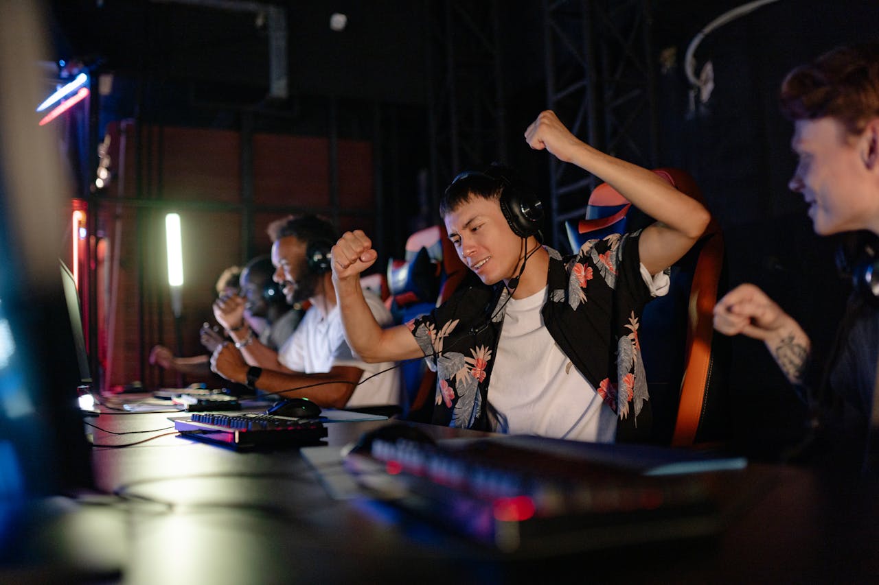 Excited gamers celebrating a win in a competitive gaming tournament with headphones.